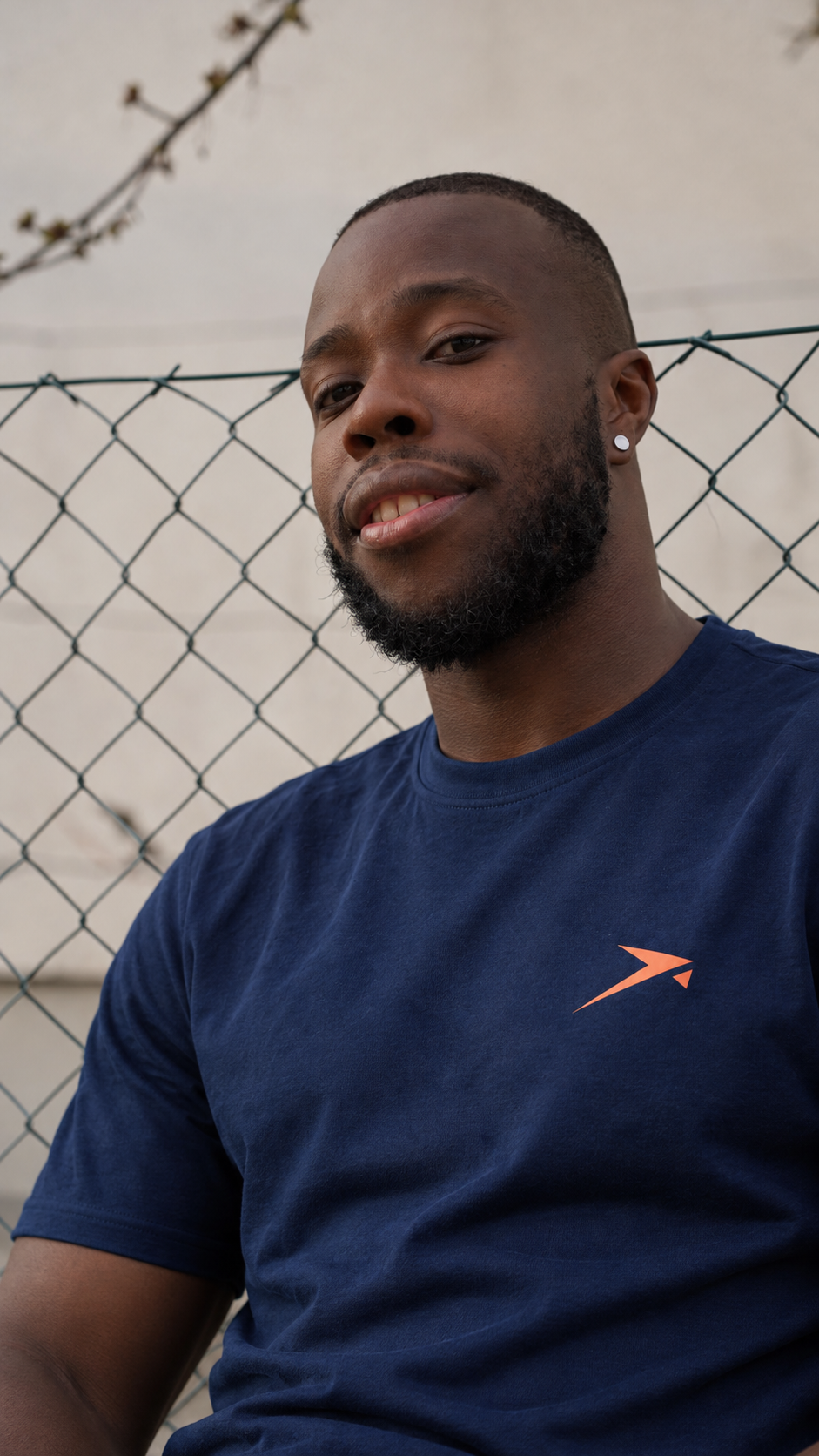 Portrait at a fence in the navy Beldi Dept. Performance T-Shirt