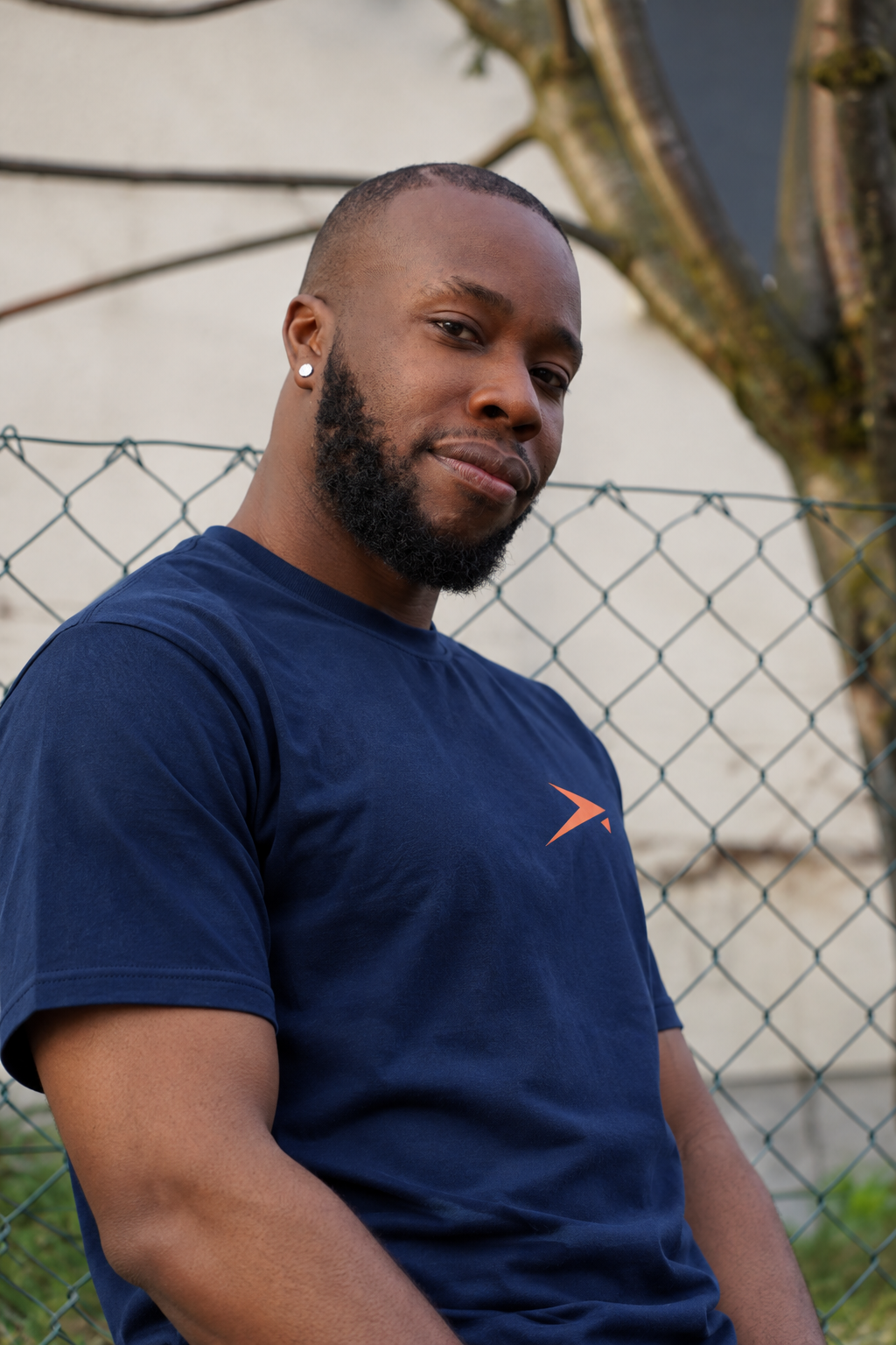 Confident portrait at a wire fence in the navy Beldi Dept. Performance T-Shirt